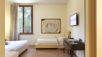 Une chambre d’hôtel avec deux lits, un bureau, une chaise, une télévision et un grand tableau représentant des fleurs accroché au mur.