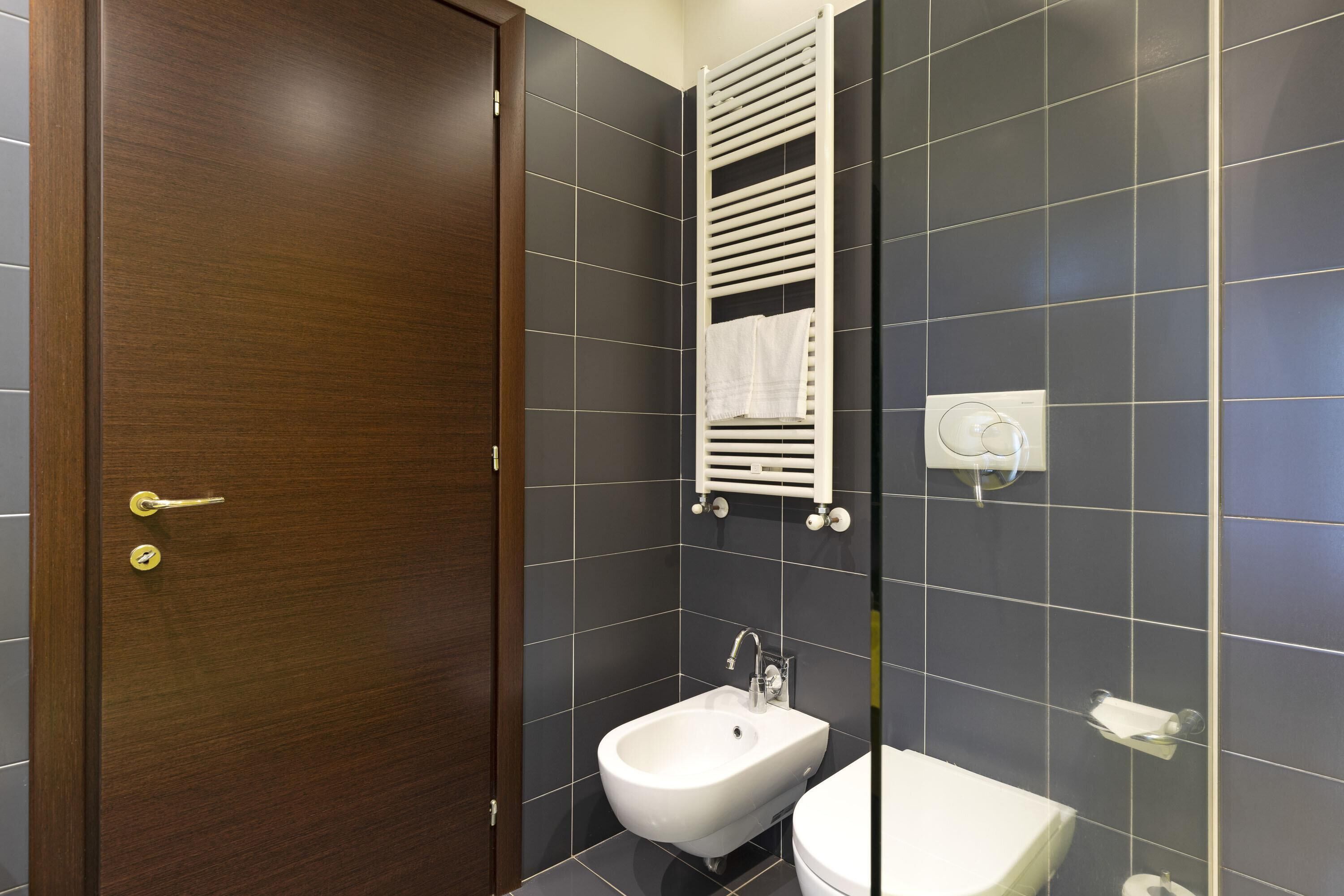 Un baño con puerta de madera, un bidé, un perchero y un inodoro.