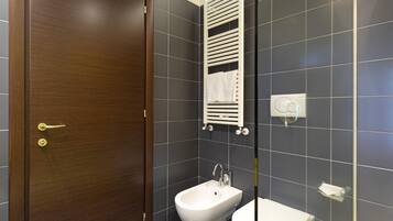 Un baño con puerta de madera, un bidé, un perchero y un inodoro.
