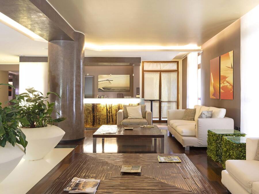 Una sala de estar moderna con una gran mesa de centro, sofás blancos y una planta grande en maceta.