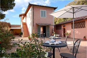 Un'area patio con mobili da esterno, un tavolo apparecchiato per mangiare e un ombrellone che offre ombra.
