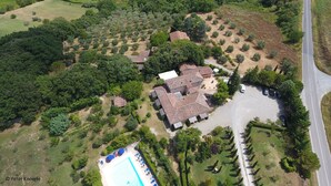 Vue aérienne d’un quartier résidentiel avec une grande maison, une piscine et de nombreux espaces verts.