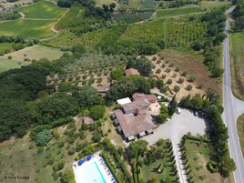 Vista aerea di una zona residenziale con una grande casa, una piscina e vegetazione circostante.
