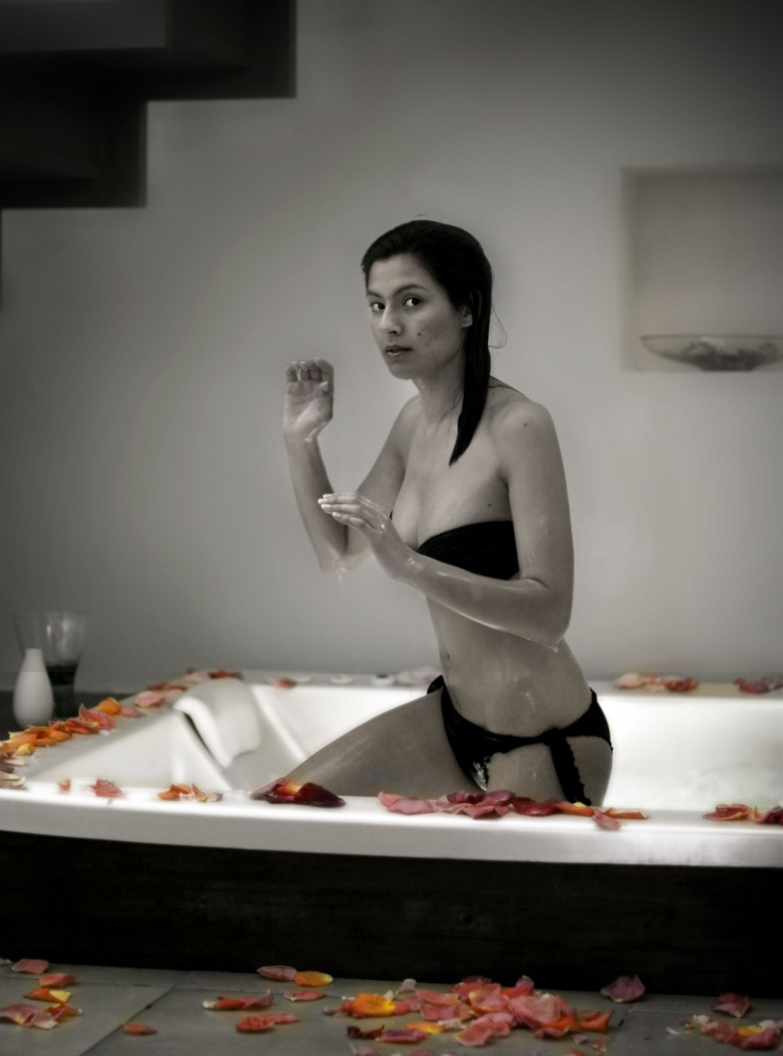 Una persona en una bañera rodeada de pétalos de rosa.
