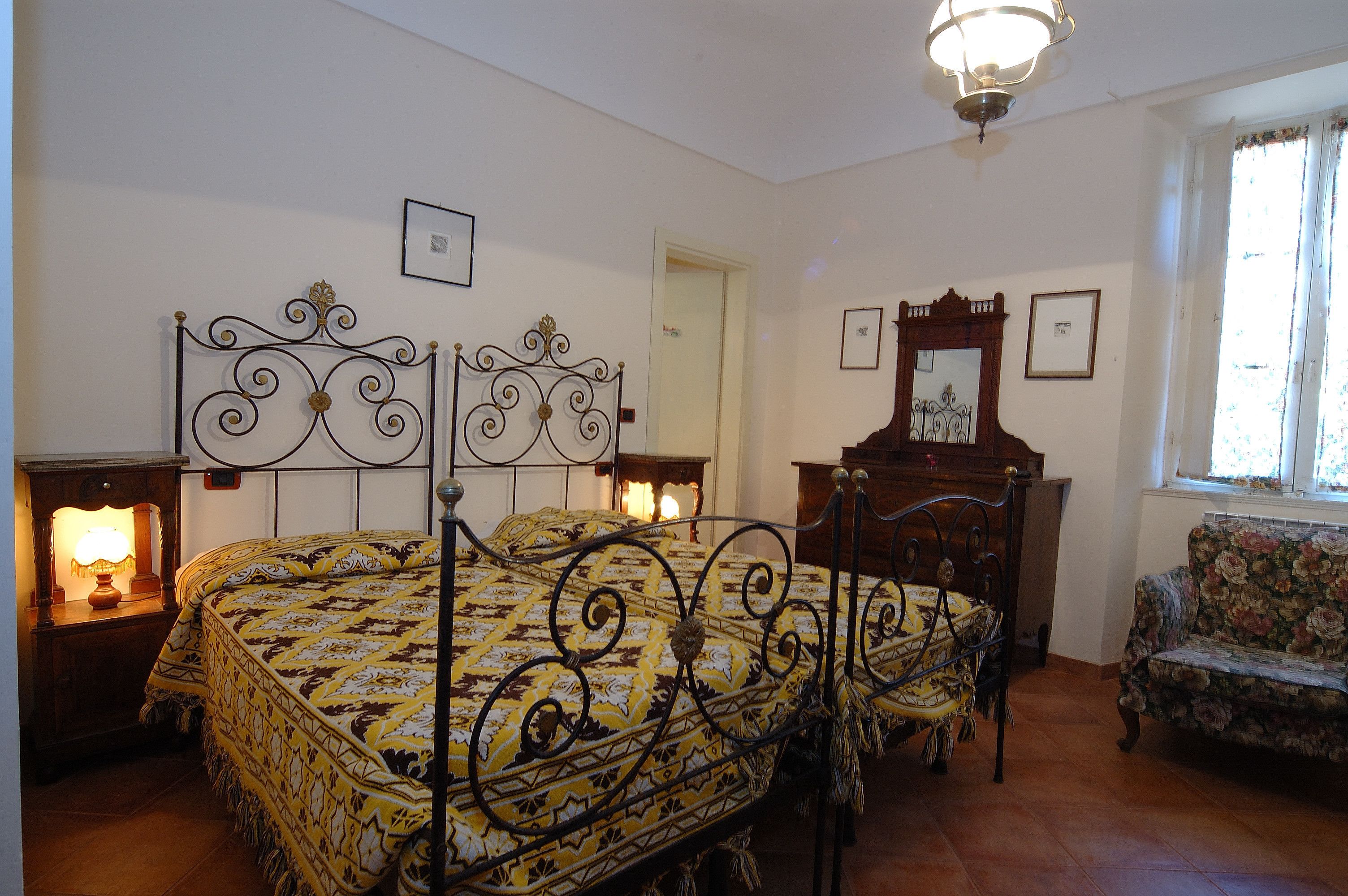 Quarto com cama, mesas de cabeceira, uma cadeira e um espelho.
