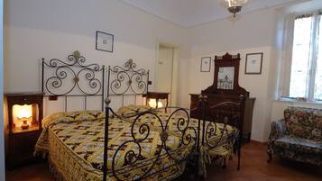 Quarto com cama, mesas de cabeceira, uma cadeira e um espelho.