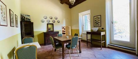 Un comedor con una mesa y sillas de madera, un armario y un ventanal con vistas al exterior.