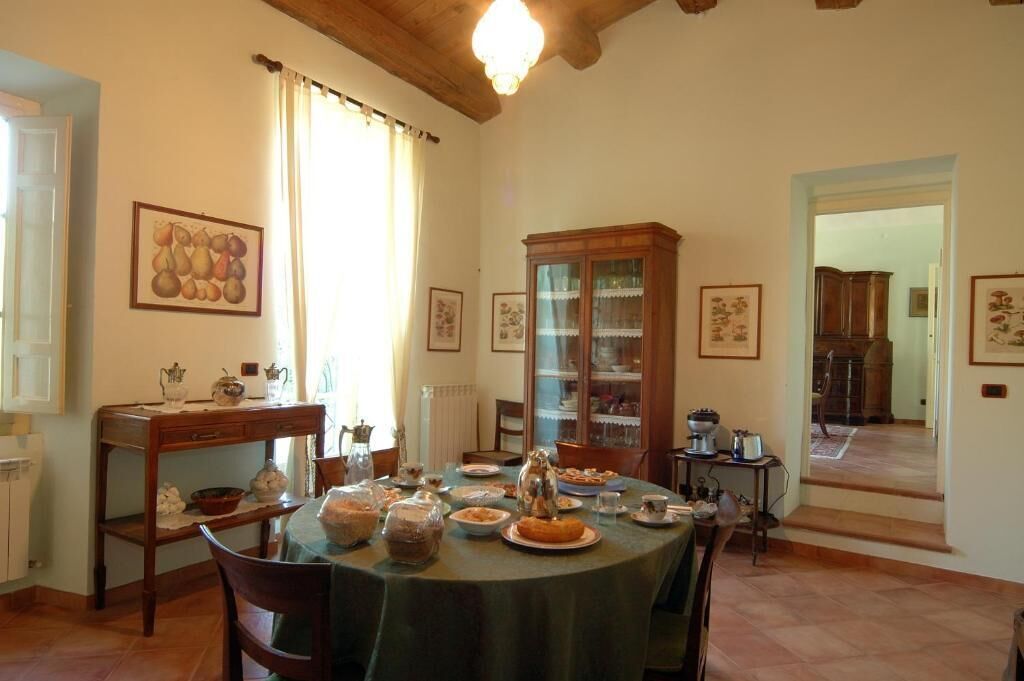A dining room with a round table set for a meal, surrounded by chairs. There is a cabinet with glass doors and a chandelier hanging from the ceiling.