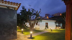 A courtyard with a stone pathway, a well-maintained lawn, and a building with a tiled roof. - Hotel Rural Casablanca (Los Realejos)