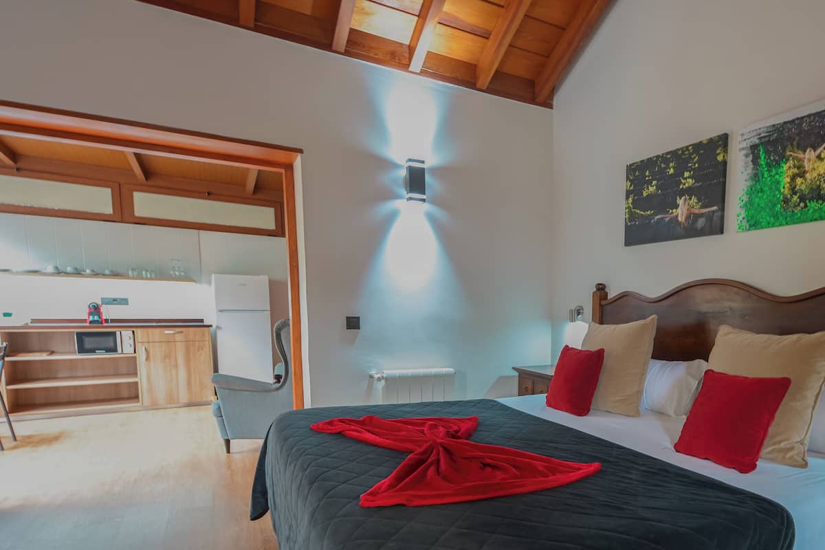 A hotel room with a bed, a nightstand, a wooden headboard, a painting, and a ceiling light.