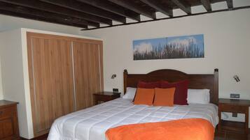 A bedroom with a wooden bed, a large wardrobe, and a painting on the wall.