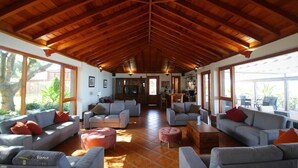 A spacious living area with a high wooden ceiling, multiple seating arrangements, and large windows offering natural light and views. - Hotel Rural Casablanca (Los Realejos)