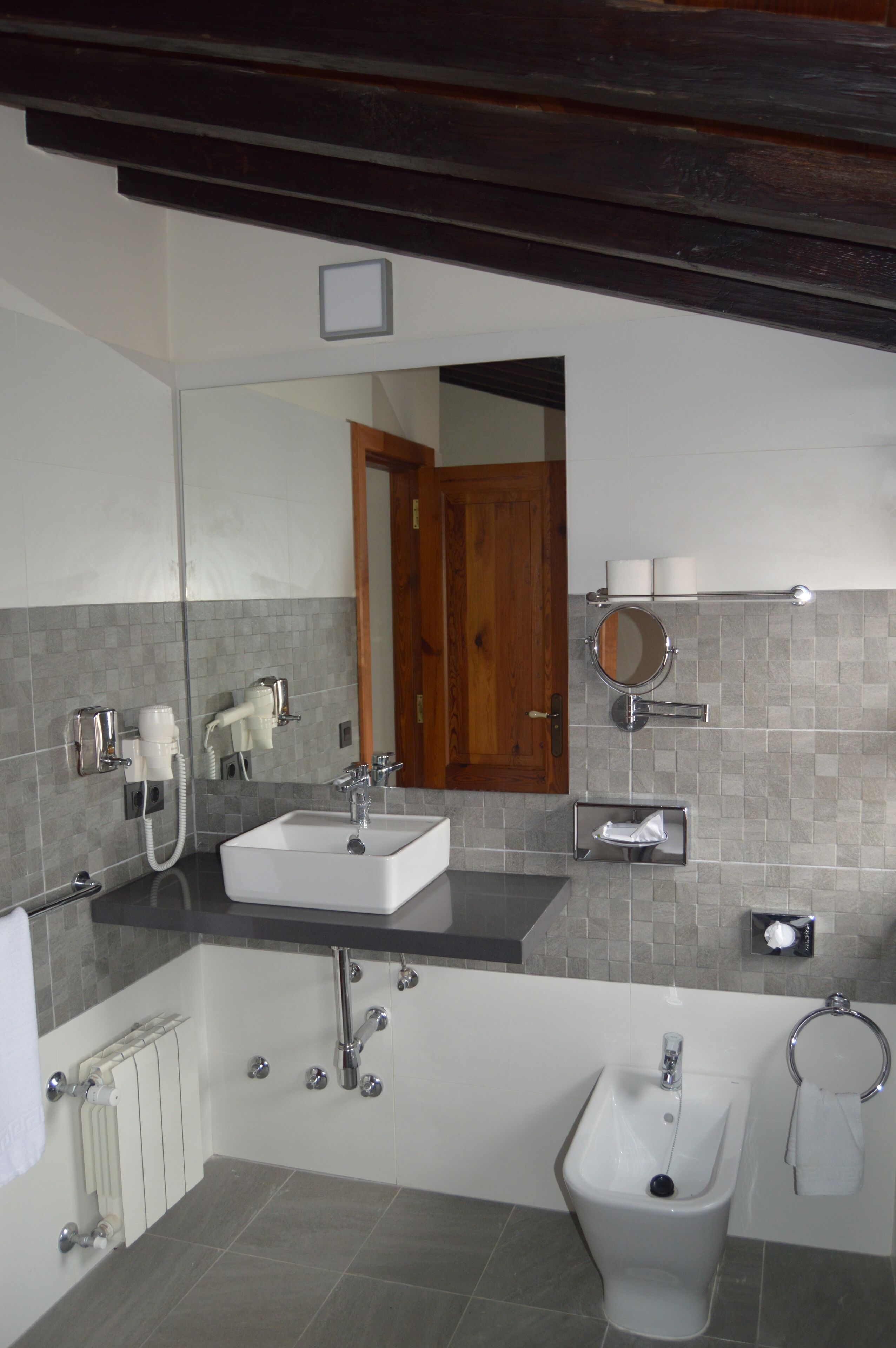 A modern bathroom with a white sink, bidet, and a mirror.