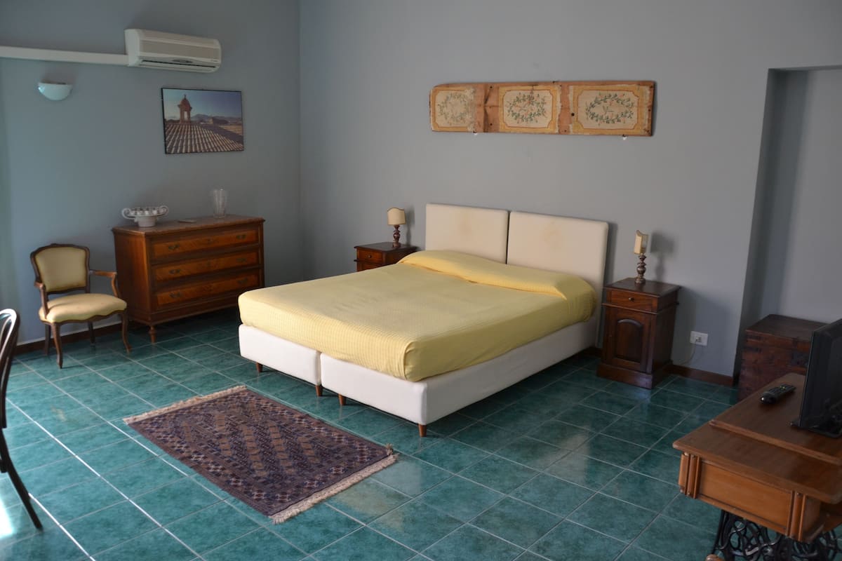 A bedroom with a bed, dresser, chair, and a small table with a lamp.