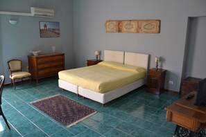 A bedroom with a bed, dresser, chair, and a small table with a lamp. - Casa Orioles (Palermo)