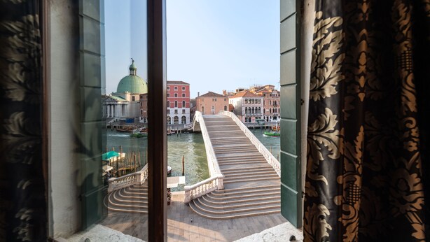 A view from a window overlooking a bridge and a domed building, with a river and boats visible. - Abbazia De Luxe (Venice)