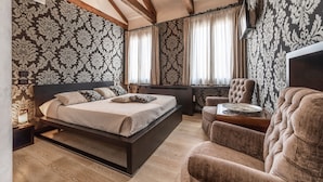 A bedroom with a bed, a chair, a desk, and a TV. - Abbazia De Luxe (Venice)