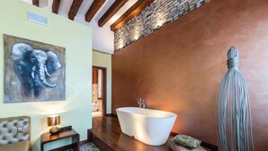 A modern bathroom with a freestanding bathtub, a stone wall, and a large elephant artwork. - Abbazia De Luxe (Venice)