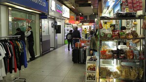 A shopping area with a clothing rack, a luggage cart, and various packaged goods on shelves. - 1ST Homestay - HK Taiwan Hostel (Kowloon)