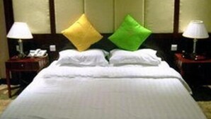 A neatly made bed with white linens and two pillows, one yellow and one green, in a hotel room with wooden headboard and nightstands with lamps. - 1ST Homestay - HK Taiwan Hostel (Kowloon)