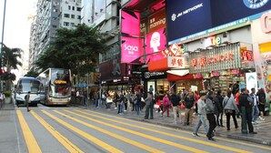 A busy urban street with pedestrians, buses, and commercial buildings. - 1ST Homestay - HK Taiwan Hostel (Kowloon)
