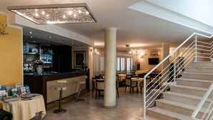 A hotel lobby with a bar area, dining tables, and a staircase. - Hotel Demar (Olbia)
