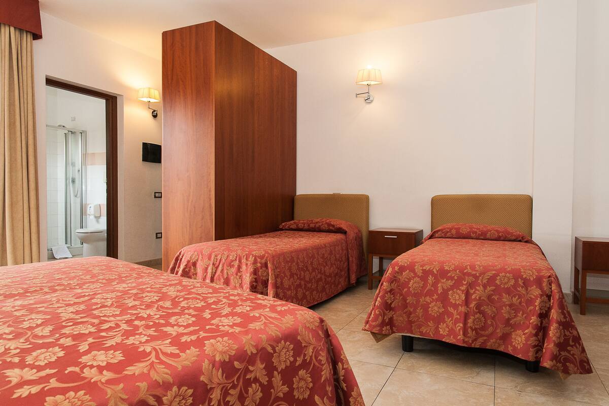 Een hotelkamer met twee enkele bedden, een wand van houten panelen en een badkamer door een open deur.