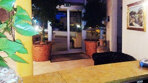 A hotel lobby with a reception desk, potted plants, and a glass door entrance. - Hotel Demar (Olbia)
