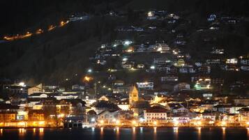 A nighttime view of a coastal town with buildings along the waterfront, a prominent church, and a hill with scattered lights.