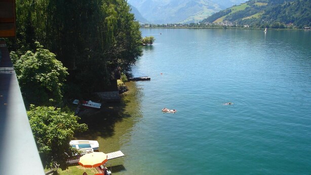 A lakeside terrace with outdoor seating and a view of the lake.