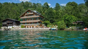 A multi-story hotel with balconies, a pool, and a forested backdrop.