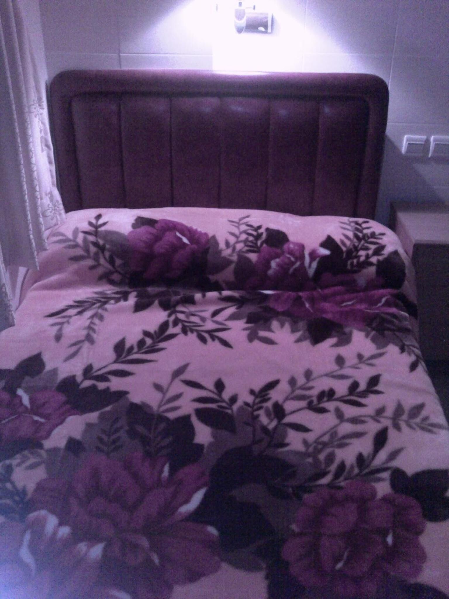A bed with a floral-patterned bedspread and a headboard.