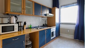 A modern kitchen with wooden cabinets, a microwave, a kettle, and a sink. - Aparthotel Vega (Berlin)
