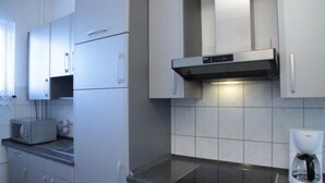 A modern kitchen with stainless steel appliances, a built-in oven, and a coffee maker. - Aparthotel Vega (Berlin)