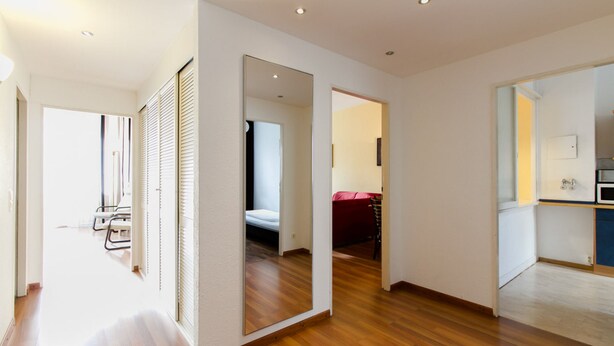 A modern interior with a wooden floor, a visible kitchen area, and a doorway leading to another room. - Aparthotel Vega (Berlin)