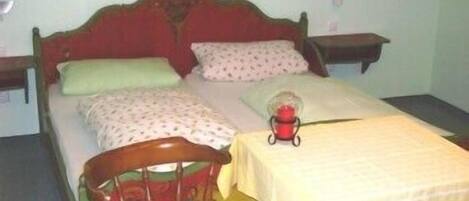 Een eenpersoonsbed met een houten hoofdbord, twee nachtkastjes en een bedlampje.