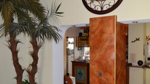 A lobby with a large clock, a palm tree, and a reception desk. - Hotel Gasthaus Café Bavaria (Inzell)