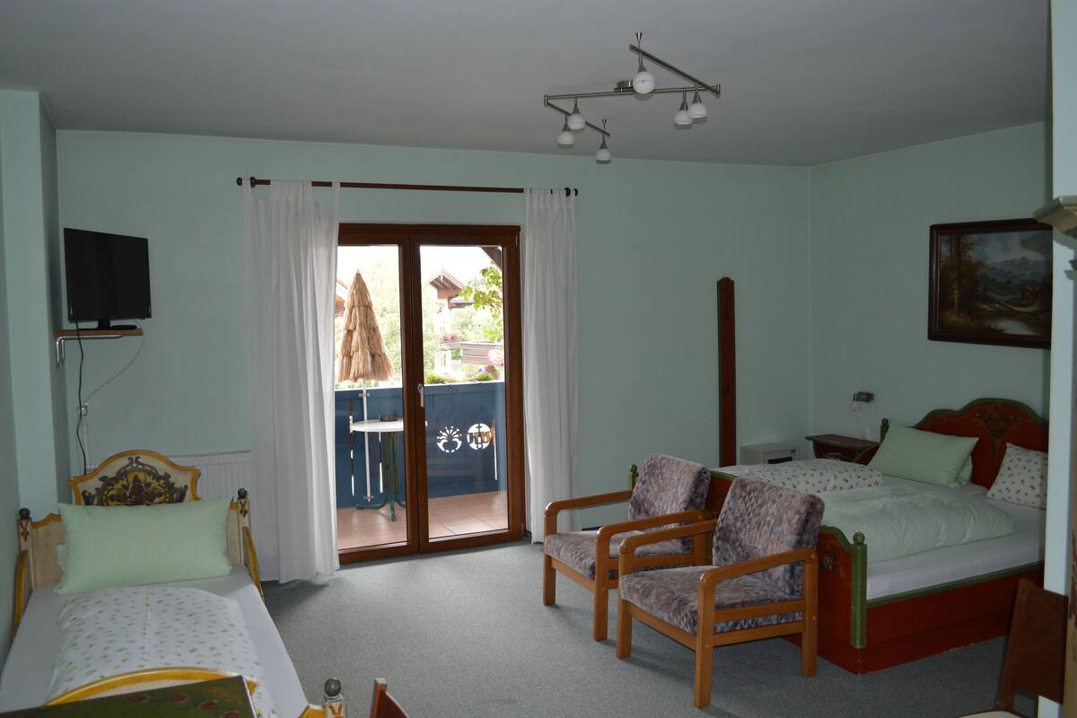 Een slaapkamer met een bed, twee stoelen, een televisie en een schilderij aan de muur.