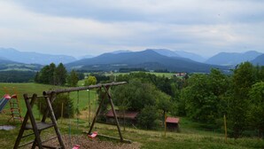 A playground with a swing set and slide, surrounded by green fields and mountains in the background. - Hotel Gasthaus Café Bavaria (Inzell)
