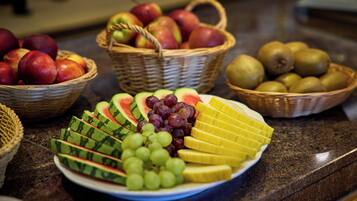 A fruit platter with watermelon, grapes, and mango slices on a kitchen counter.