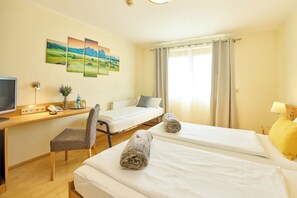 Ein Hotelzimmer mit zwei Betten, einem Schreibtisch mit Computer, einem Stuhl und einem Fernseher.