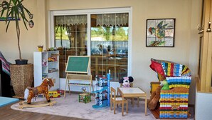 Un espace de jeux intérieur accueillant, avec un cheval à bascule, une chaise à l’effigie de Minnie Mouse et une bibliothèque.