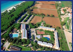 Vista aerea di un resort con diversi edifici, una spiaggia e campi circostanti.