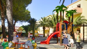A playground with various play structures, including a slide and a ride-on toy. - Hotel Oasis (Alghero)