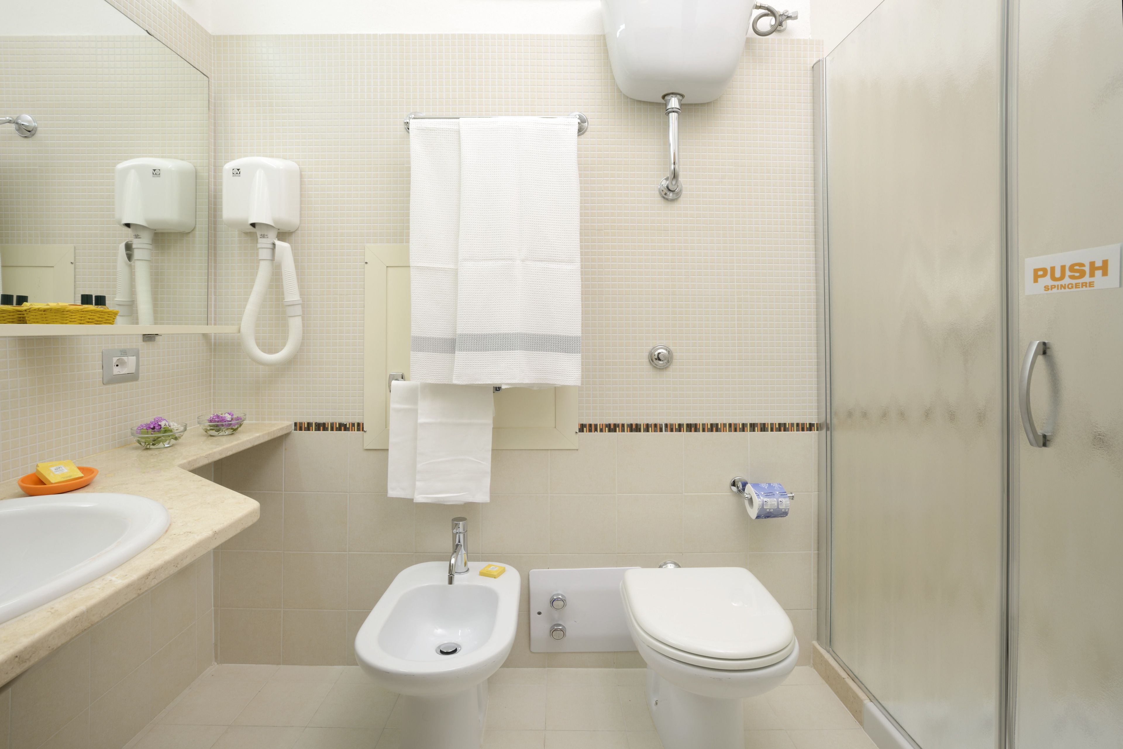 Un baño con bidé, inodoro, lavamanos y perchero para toallas.