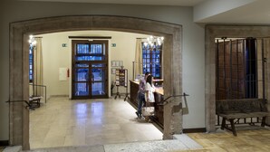 A lobby with a reception desk, a bench, and a large arched doorway.