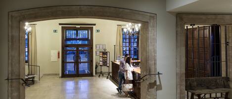 A lobby with a reception desk, a bench, and a large arched doorway.