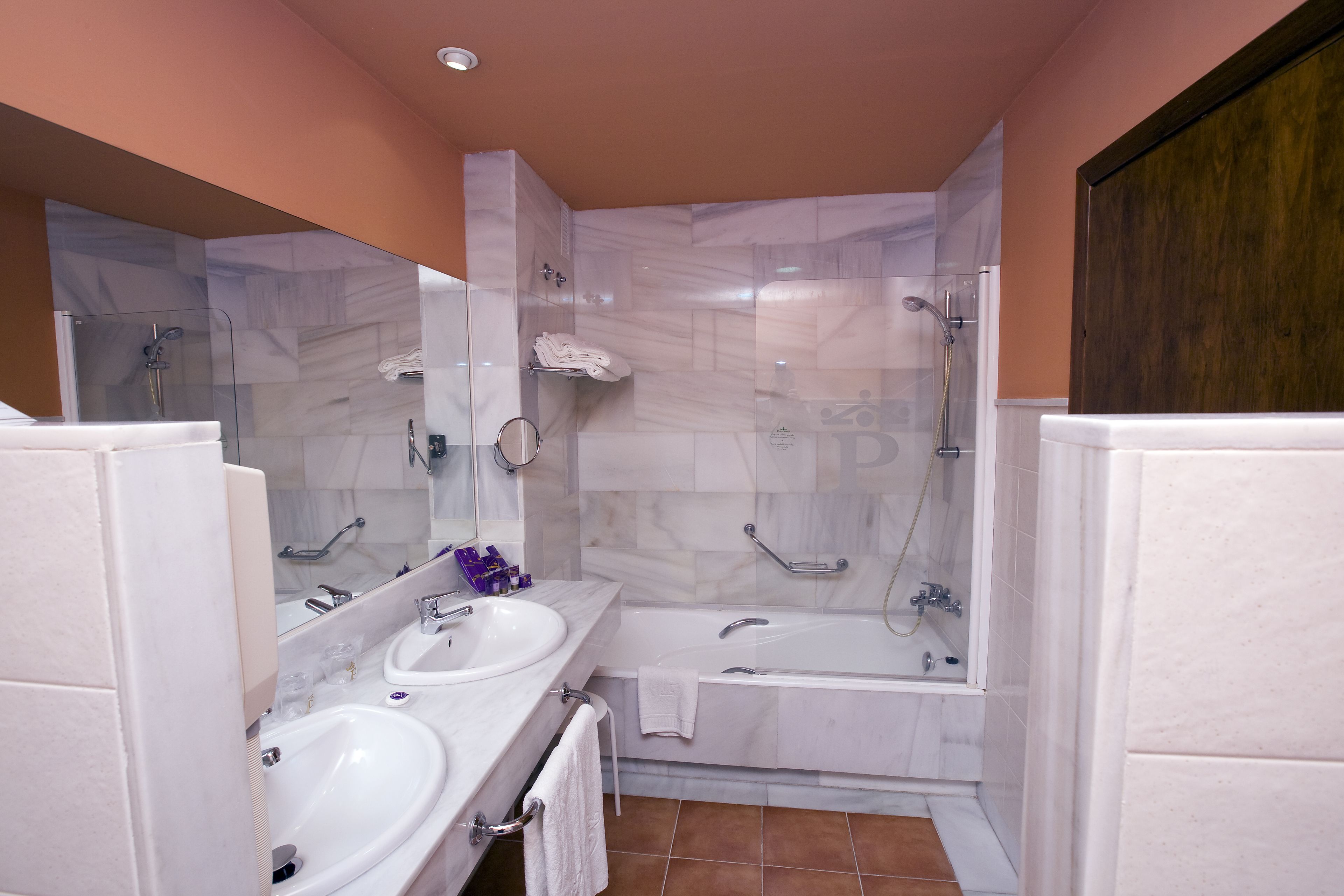 Un baño con dos lavamanos, una bañera y una ducha.