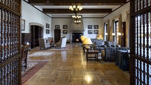 A spacious living room with a fireplace, wooden floors, and a chandelier.