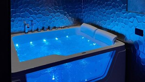 Une salle de bain moderne dotée d’une grande baignoire, de murs à texture et d’un plafond pourvu d’un éclairage encastré.